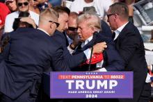 Republican presidential candidate and former U.S. President Donald Trump is assisted by guards during a campaign rally after shots were reportedly fired at the Butler Farm Show in Pennsylvania July 13, 2024. A local prosecutor says the suspected gunman and at least one attendee are dead. 
