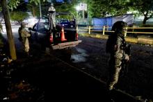 Two armed soldiers stand in a street at night.