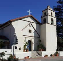 The front of church with bell tower and tiled roof. 