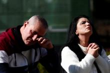 A woman prays as a man reacts next to the statue of St. John Paul II outside Rome's Gemelli Hospital Feb. 20, 2025, where Pope Francis is admitted for treatment for a respiratory infection. (OSV News photo/Guglielmo Mangiapane, Reuters)