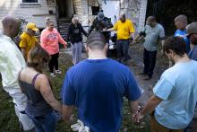 Group circled in prayer outside of house. 